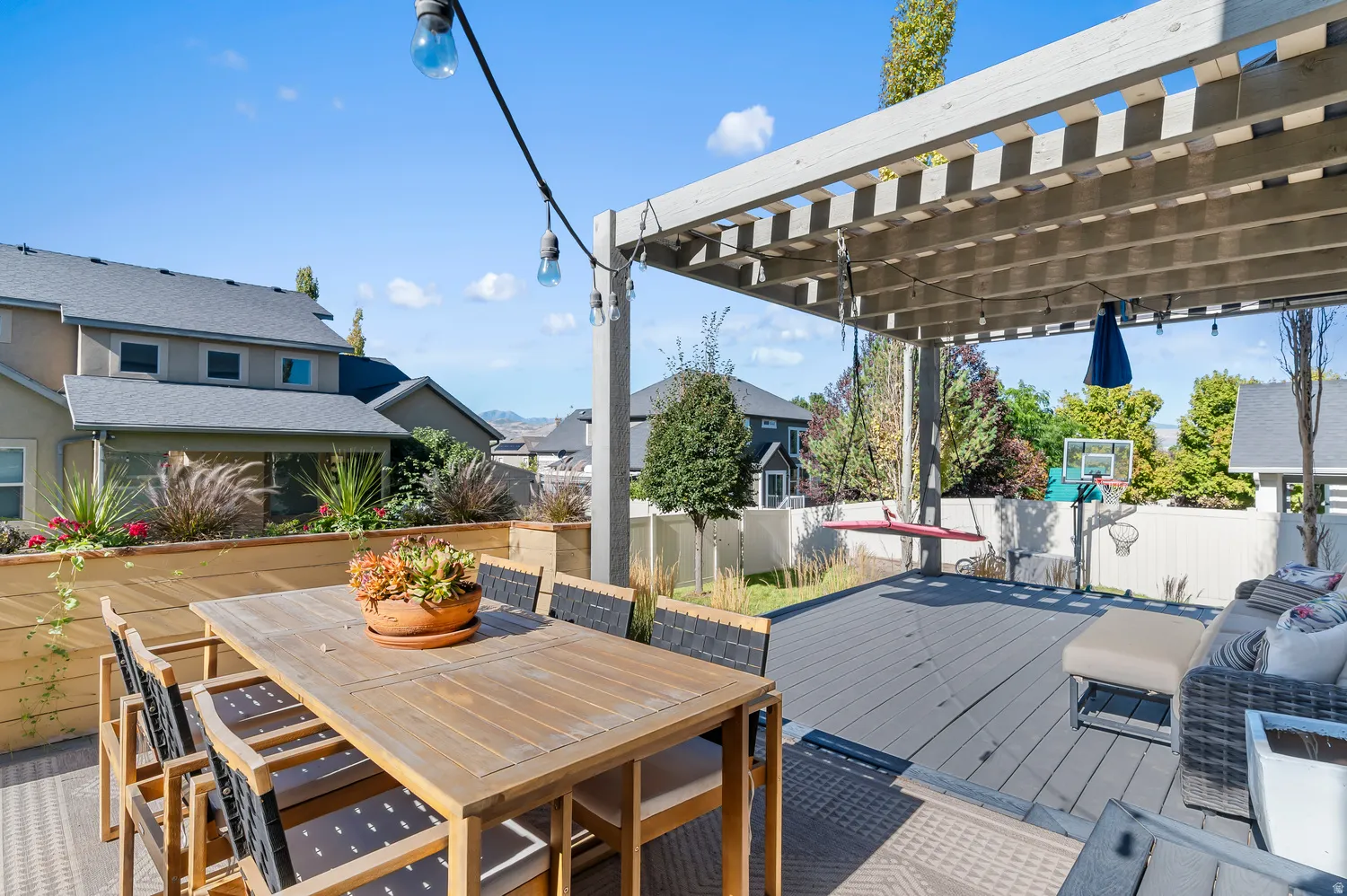 Deck with a wood pergola, string lighting, and an integrated planter box