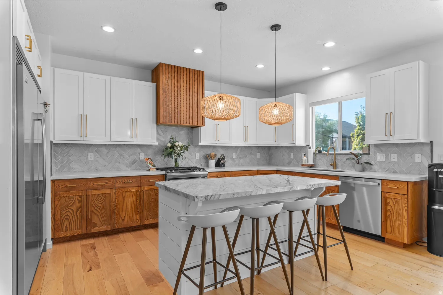 Kitchen featuring an expansive center island with seating, stainless steel appliances, wood-finish flooring, two-tone cabinetry, and a patterned backsplash