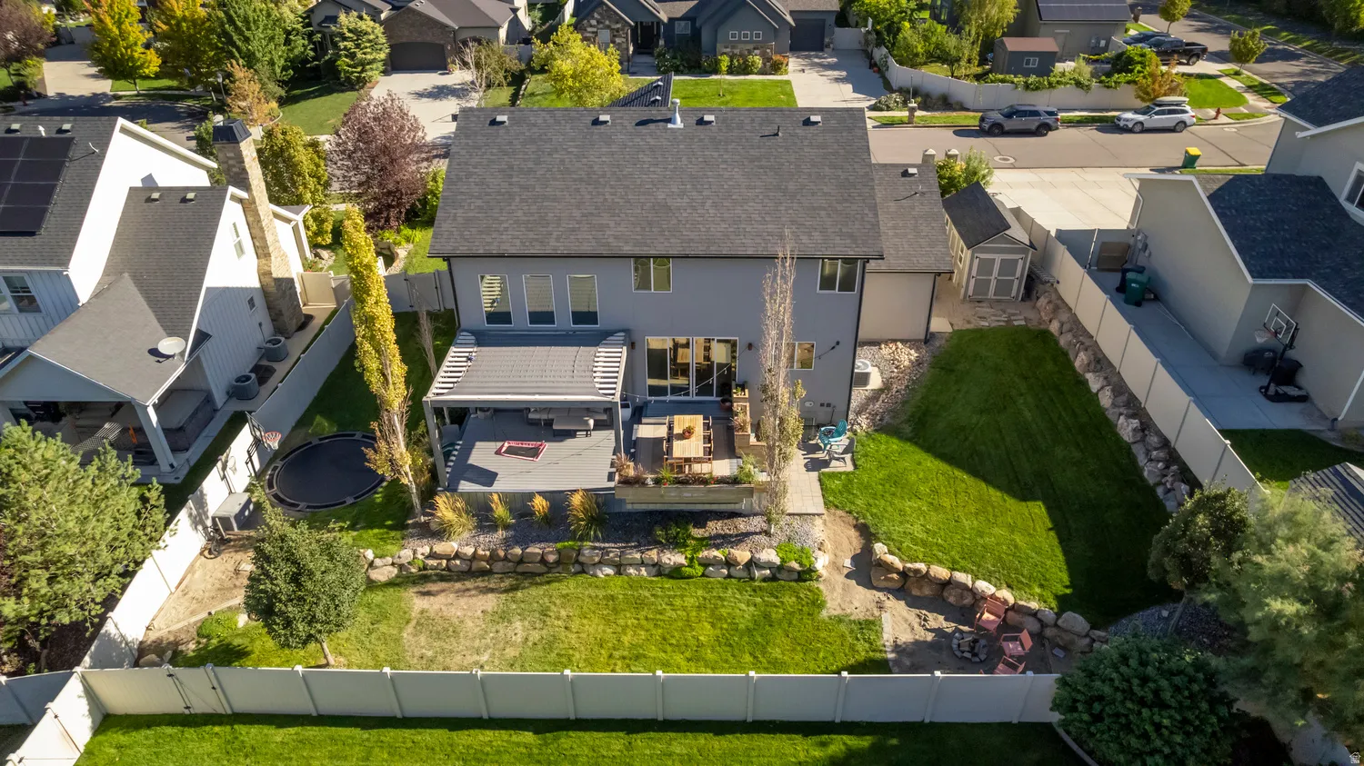 Expansive rear exterior featuring a multi-level patio, built-in pergola, and a vibrant green lawn