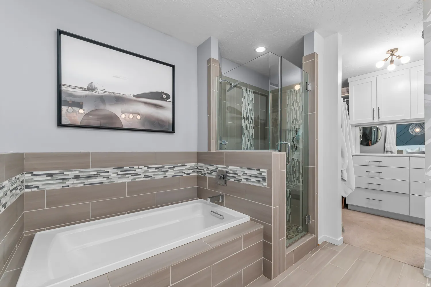Built-in soaking tub with tile surround, glass-enclosed shower, wood-finish flooring, and recessed lighting