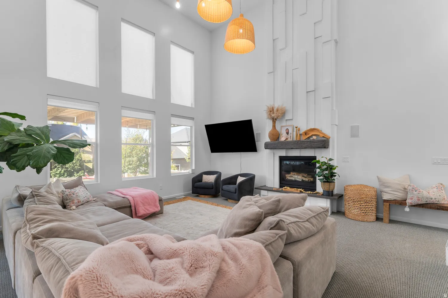 Vaulted ceiling with decorative wall paneling, built-in fireplace, multiple large windows, and built-in overhead lighting