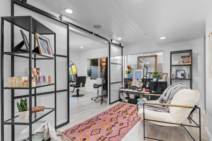 Sliding barn doors with frosted glass panels, recessed ceiling lighting, light wood-finish flooring, white shiplap ceiling, and built-in shelving with metal frames