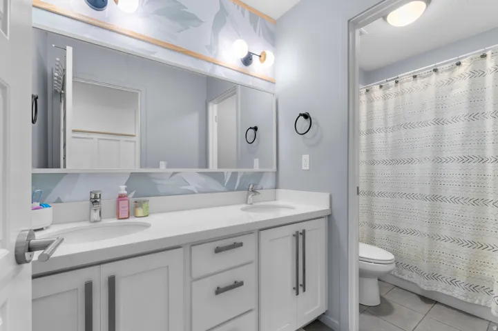 Double vanity with integrated sinks, white cabinetry, and matte black hardware