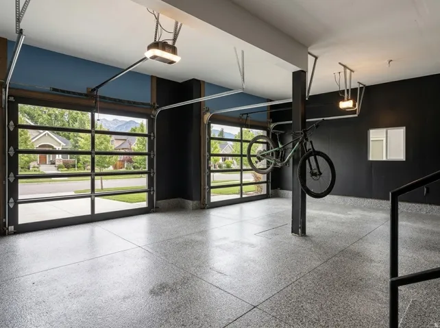 Garage featuring two full-view garage doors with automatic openers, an epoxy flake floor, and a mounted storage rack