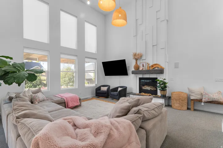 Vaulted ceiling with decorative wall paneling, built-in fireplace, multiple large windows, and built-in overhead lighting