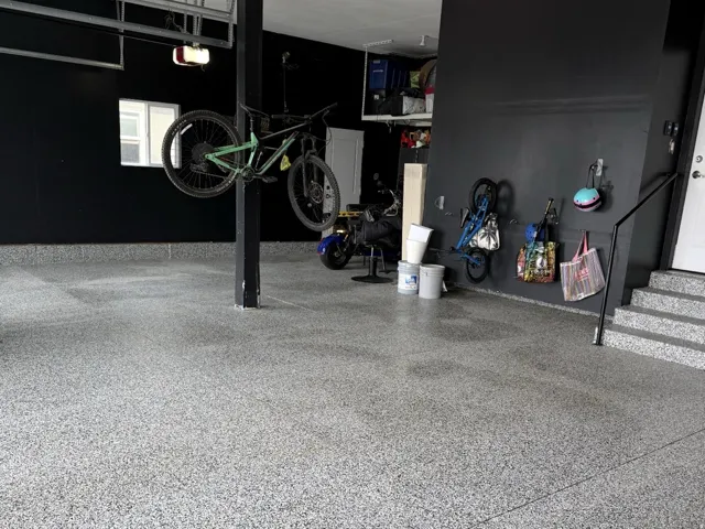 Textured garage flooring, dark wall finishes, and integrated overhead storage