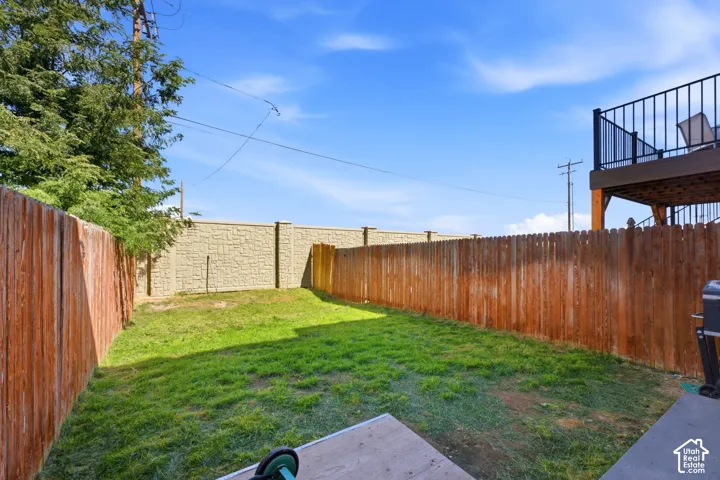 Expansive backyard with a manicured lawn, wood fencing, and a block wall perimeter