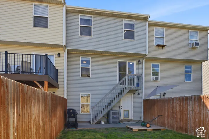 Multi-level exterior with siding, a privacy fence, a ground-level patio, and an upper-level deck with black railing