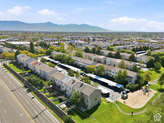 Aerial perspective showcasing townhomes, covered parking structures, a playground area, and surrounding green spaces with mature trees