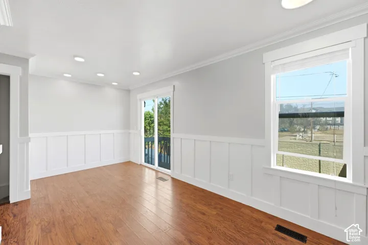 Wood-finish flooring, recessed lighting, white wainscoting, sliding glass door, and a framed window