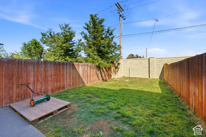 Expansive grassy yard with wood fencing and a textured stone wall