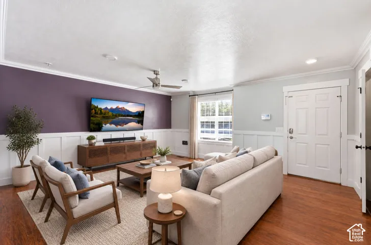Wood-finish flooring with white wainscoting, a paneled entry door, and a ceiling fan with integrated lighting