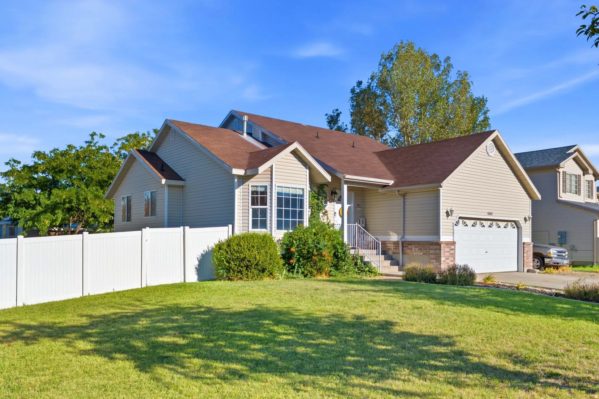 Exterior featuring siding, brick accents, a gabled roof, an attached garage, and a white fence