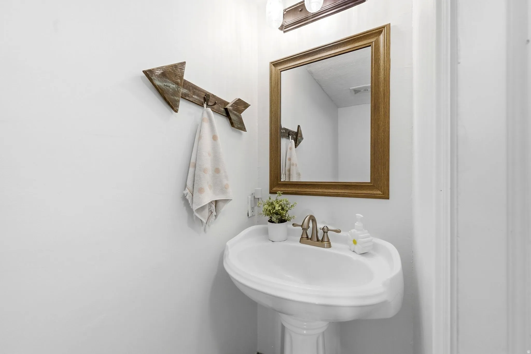 Pedestal sink with a dual-handle faucet and a framed mirror