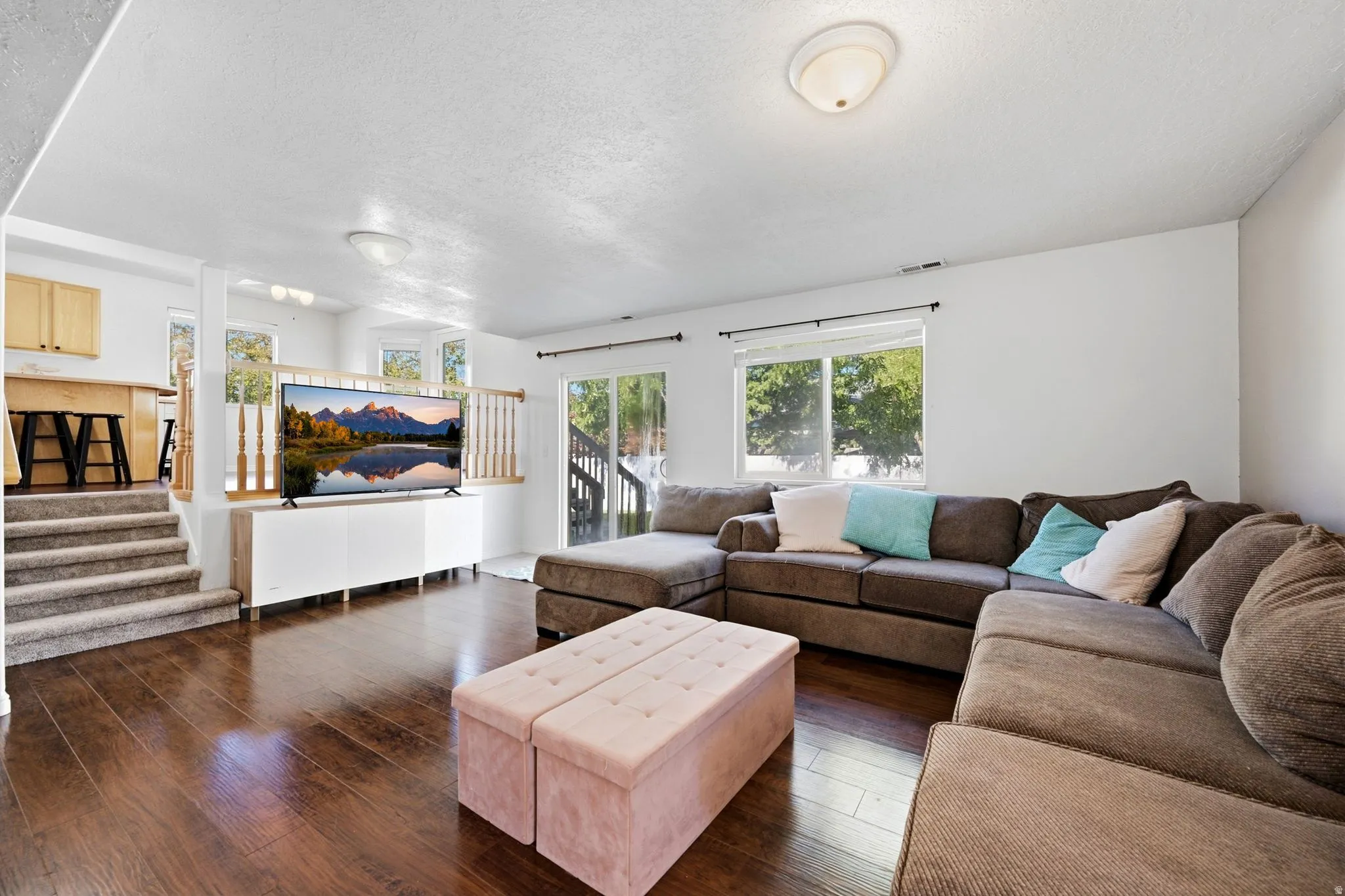 Hardwood-finish flooring, white walls, multiple windows, and a sliding glass door