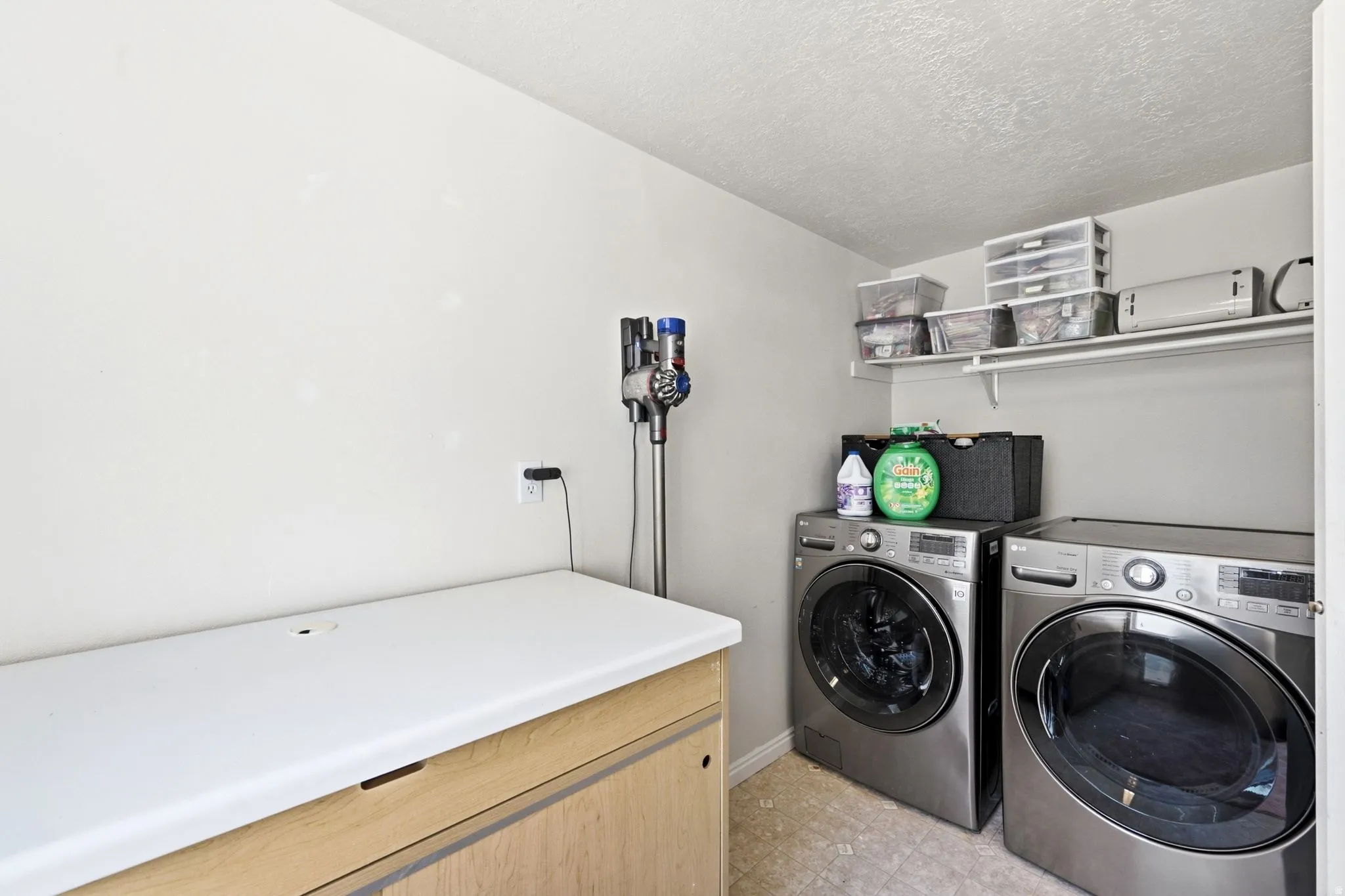 Dedicated laundry area featuring a built-in counter, open shelving, and wall-mounted storage