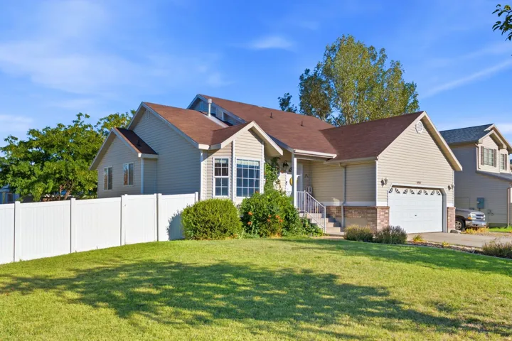 Exterior featuring siding, brick accents, a gabled roof, an attached garage, and a white fence