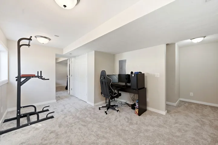 Carpeted interior space featuring neutral wall tones, overhead dome lighting, white trim, and a white bi-fold door