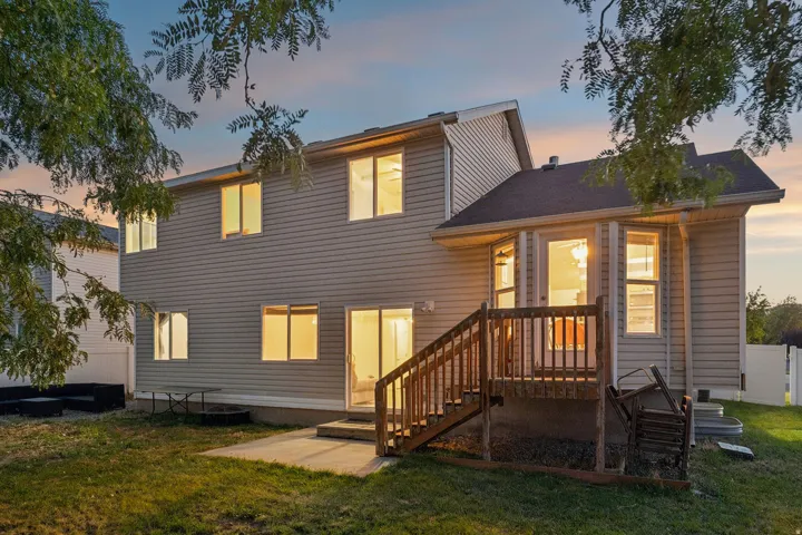 Two-story exterior with siding, featuring multiple windows, a rear deck, and a ground-level patio