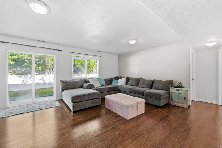 Wood-finish flooring, white walls, recessed ceiling lighting, sliding glass door, and a single window