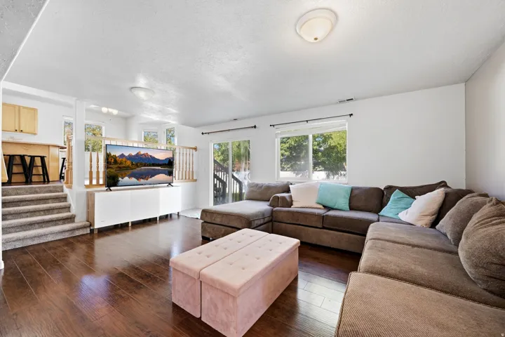 Hardwood-finish flooring, white walls, multiple windows, and a sliding glass door