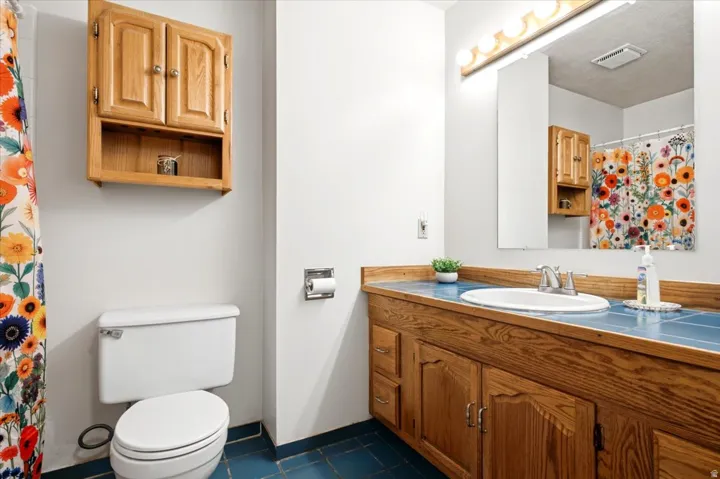 Wood-finish vanity with an integrated sink and tiled countertop, complemented by a large wall mirror