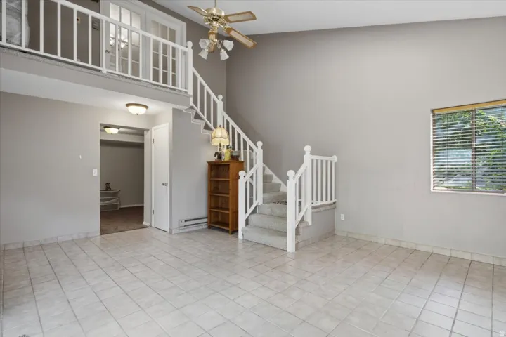 Tile flooring, open-concept living area, high ceilings, ceiling fan, and an interior balcony