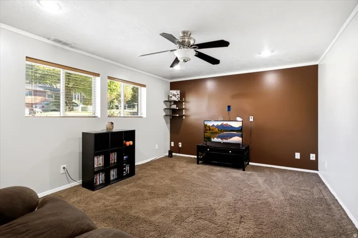 Recessed lighting, ceiling fan, brown accent wall, and multiple windows