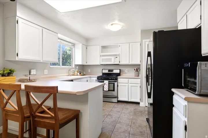 Kitchen featuring white cabinetry, light-toned countertops, a stainless steel range, and tile flooring