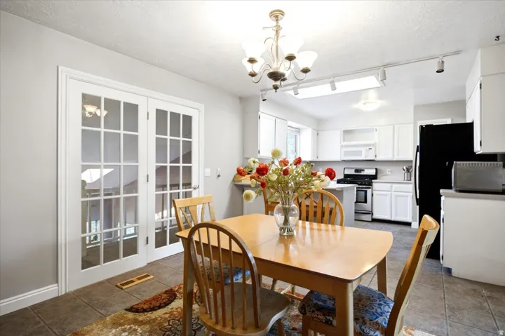 French doors with grid panels, tile flooring, white cabinetry, integrated kitchen appliances, and track lighting