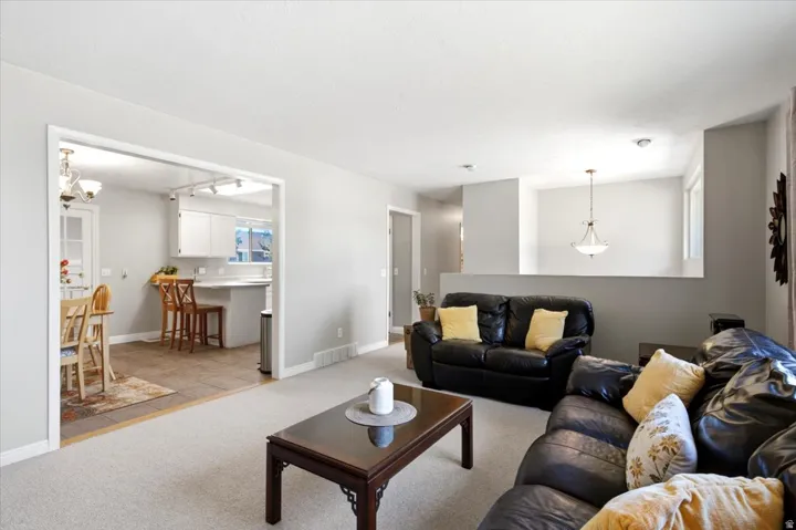 Recessed lighting, light gray wall color, carpeted flooring, kitchen with white cabinetry, and a peninsula countertop