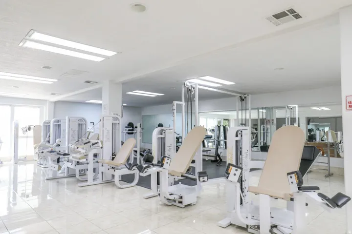 Fitness center featuring large windows, tiled flooring, built-in mirrors, and multiple exercise machines