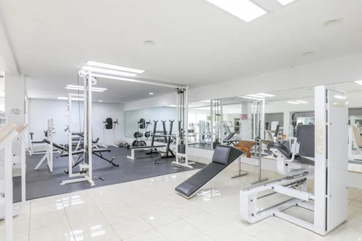 Fitness center with white tile flooring and extensive mirrored walls