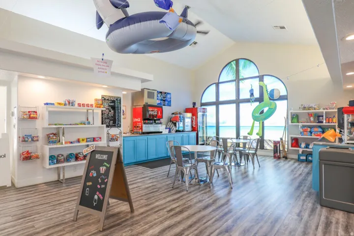 Vaulted ceiling with a ceiling fan, arched windows, wood-finish flooring, built-in shelving, and light blue cabinetry