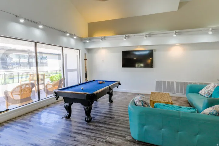 Spacious common area featuring wood-finish flooring, a vaulted ceiling, and track lighting