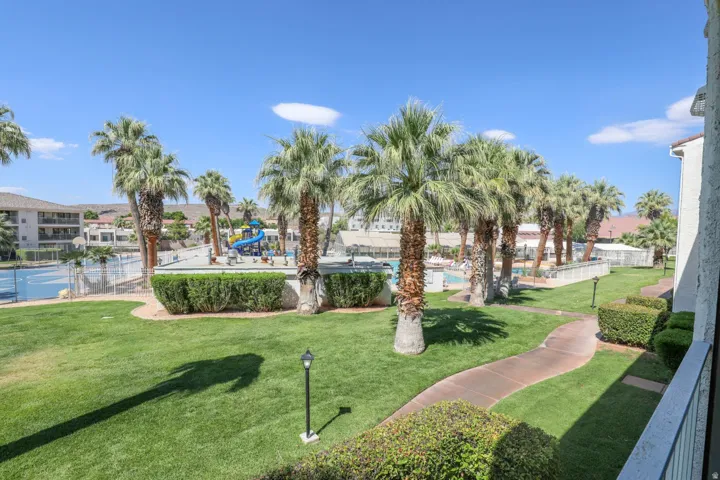 Landscaped grounds with a paved pathway, mature palm trees, and manicured shrubbery