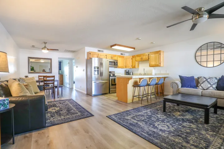 Open-concept living area featuring wood-finish flooring, a kitchen with wood cabinetry and stainless steel appliances, a dining area, and ceiling fans