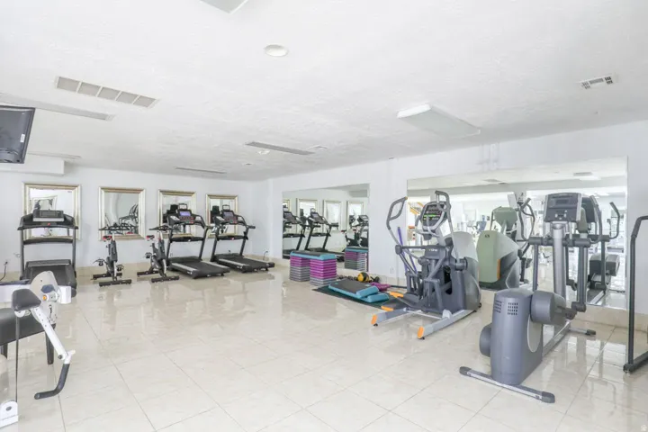 Fitness area with tile flooring, mirrored walls, and built-in lighting