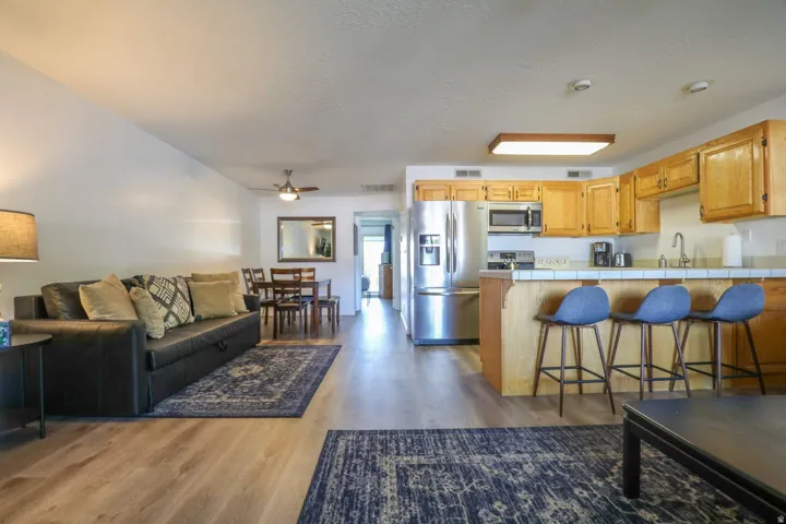 Open-concept living area with wood-finish flooring, stainless steel appliances, and a breakfast bar with seating