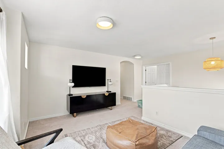 Carpeted area featuring a half-wall, arched doorway, and a built-in entertainment console