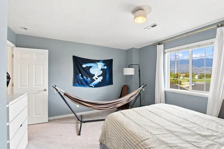 Light gray wall paint, window with white trim, white paneled door, flush-mount ceiling light fixture, and light-colored carpeting