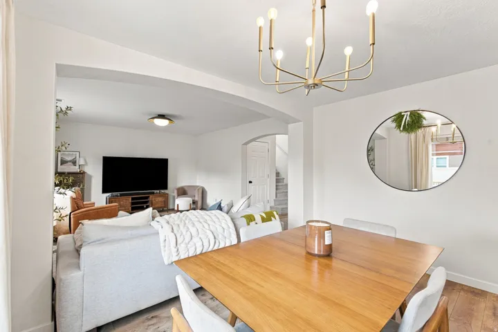 Open concept living space with a brass chandelier, arched doorway, and wood-finish flooring
