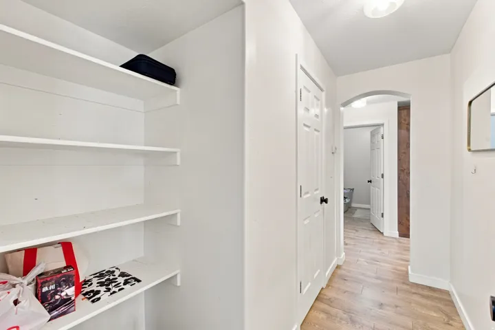Hallway featuring wood-finish flooring, an arched doorway, and a ceiling-mounted light fixture