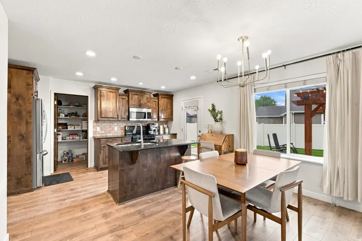 Open-concept kitchen and dining area featuring wood-finish flooring, recessed lighting, and a kitchen island with built-in sink