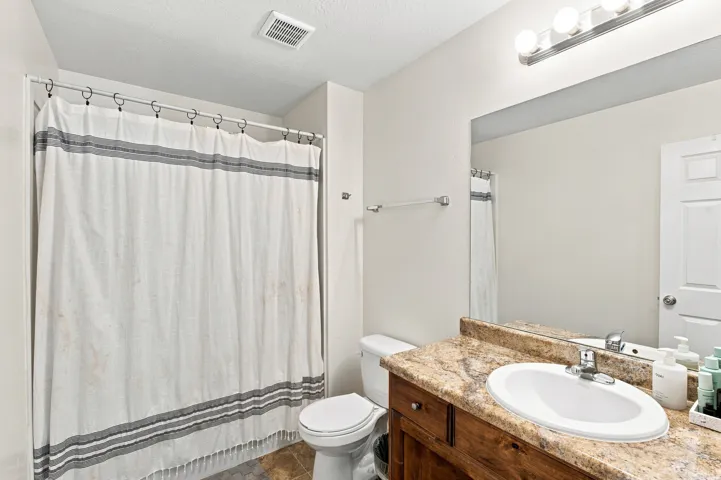 Single vanity with a surface-mount sink, chrome faucet, and wood-finish cabinetry