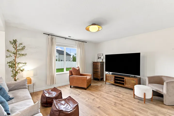 Recessed lighting, wood-finish flooring, and a large window with privacy fencing