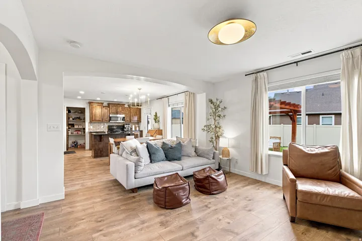 Open-concept living area featuring wood-finish flooring, an arched entryway, recessed lighting, and a modern ceiling fixture