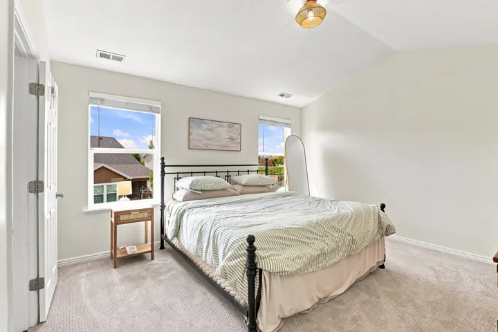 Vaulted ceiling with a flush-mount light fixture, two windows, and light-toned carpeting
