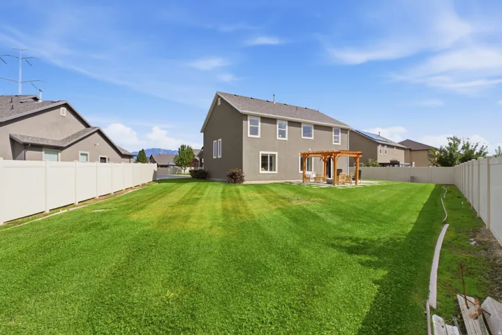 Expansive backyard featuring a manicured lawn, a wooden pergola, and a privacy fence