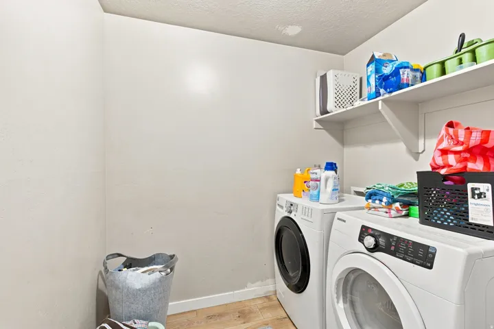 Laundry area with open shelving and wood-finish flooring